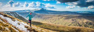Active teenager trail running along rocky path high in the picturesque mountain wilderness of the Brecon Beacons National Park, Wales. ProPhoto RGB profile for maximum color fidelity and gamut.
