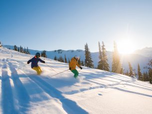 Couple skiing on a sunny powder day