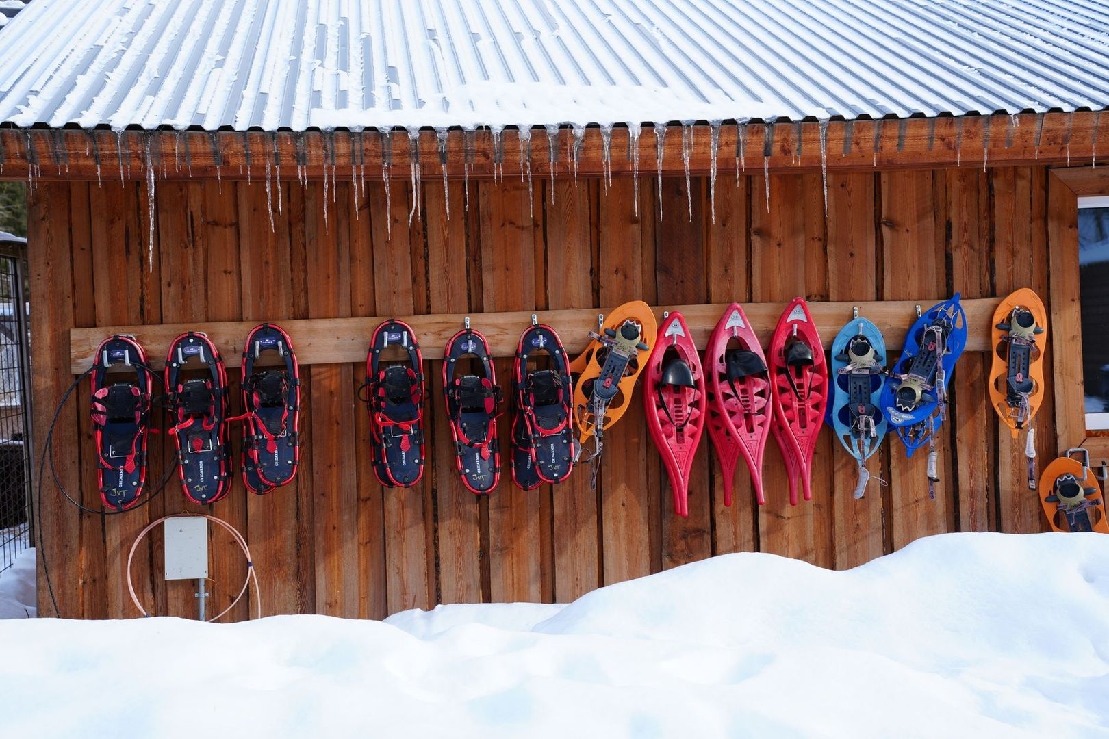 Snøsko og truger henger til tørk under et snødekt tak